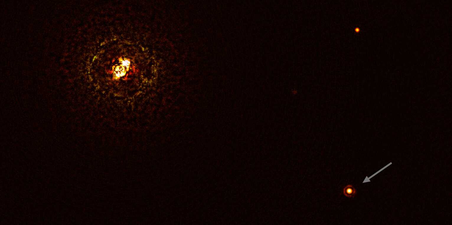 Dieses mit dem SPHERE-Instrument am Very Large Telescope der ESO aufgenommene Bild zeigt das massereiche Sternsystem b Centauri und seinen Riesenplaneten b Centauri b (Pfeil). Der andere helle Punkt im Bild (oben rechts) ist ein Hintergrundstern. (Aufnahme: ESO/Janson et al.)