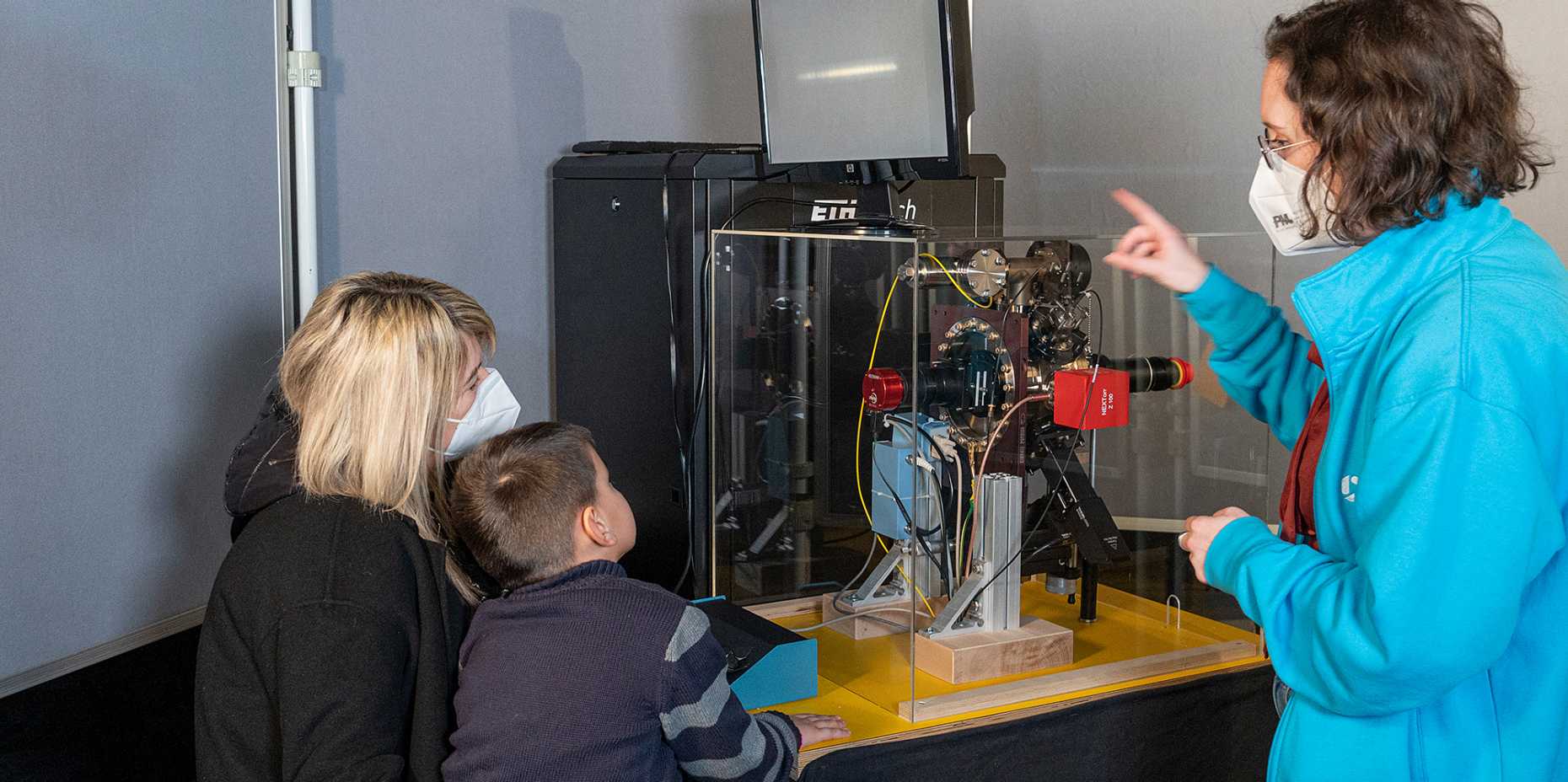 Even the smallest ones want to see the small particles: Natascha Hedrich with two guests at a public test of the ion trap at Technorama. (Photo: ETH Zurich/ Heidi Hostettler)