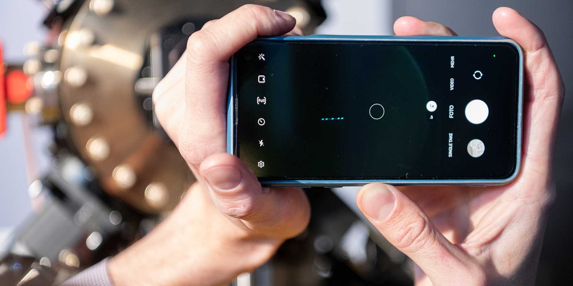 At Technorama, engineer Ilia Sergachev uses his cell phone to photograph the ions made visible in the trap. This is possible because barium was chosen as the atomic species. The great advantage of barium is that it emits many photons per second and the human eye is very sensitive to the green colour of its laser cooling transition. (Photo ETH Zurich / Heidi Hostettler)