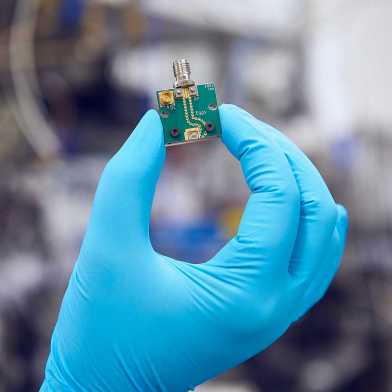 A gloved hand holding the chip used in the experiment