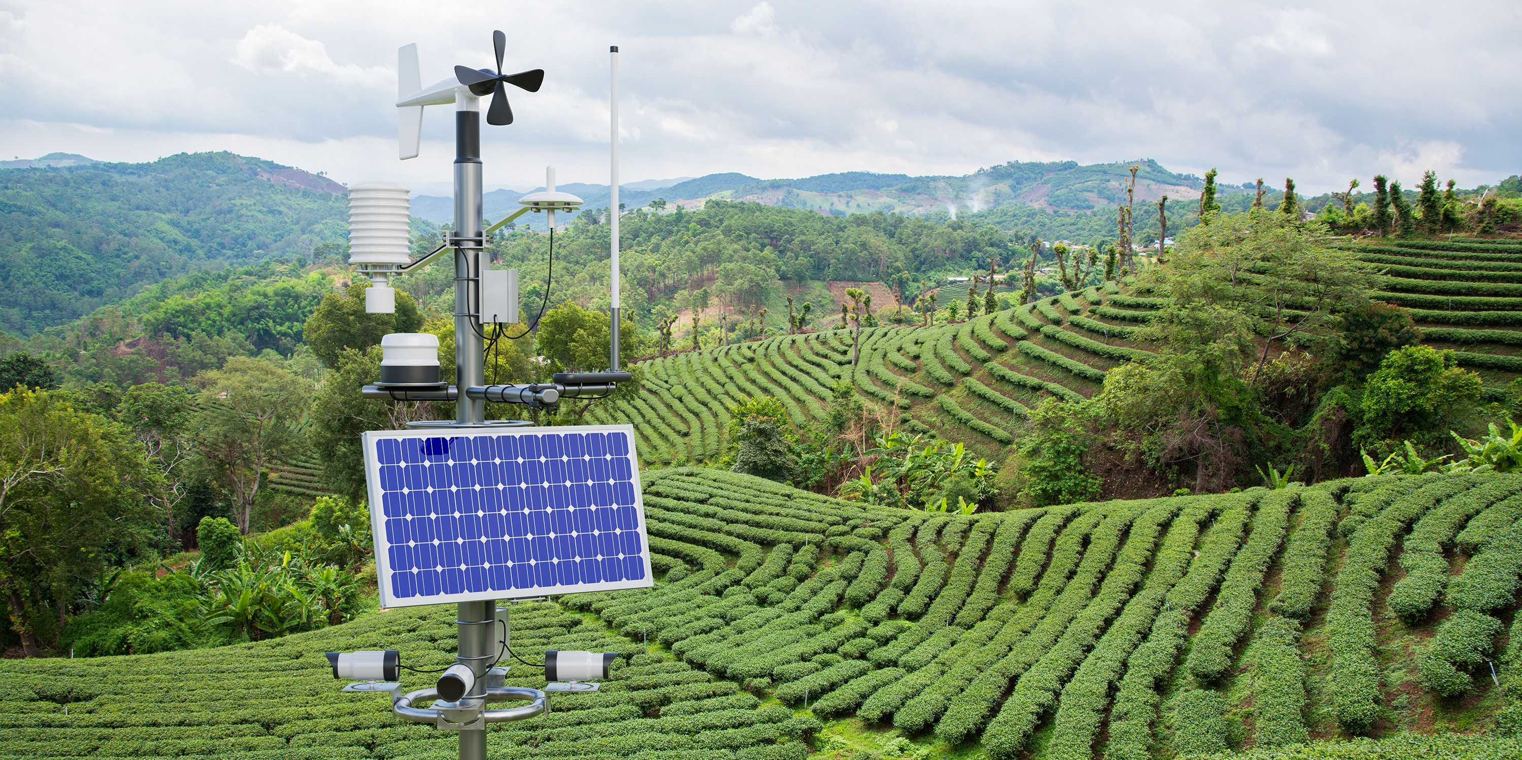 Photo of an outdoors weather monitoring station with various sensors, with green hills in the background
