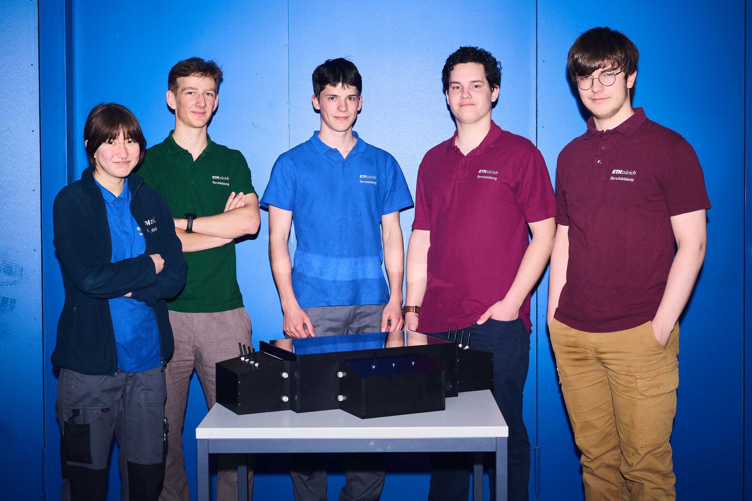 Five apprentices stand behind a table and present their laser labyrinth