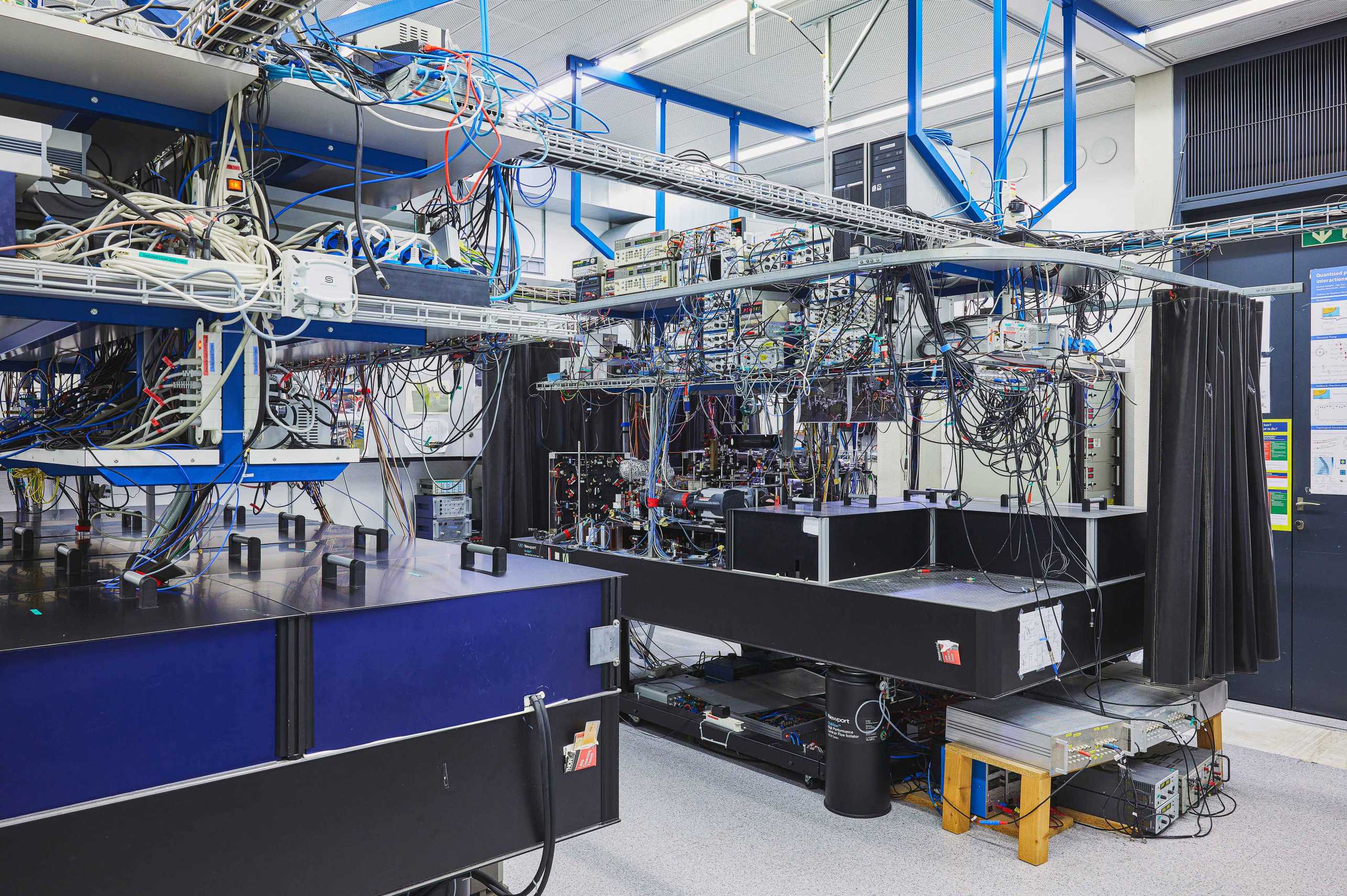 Photo showing two optical tables in a physics laboratory with electronic equipment above them